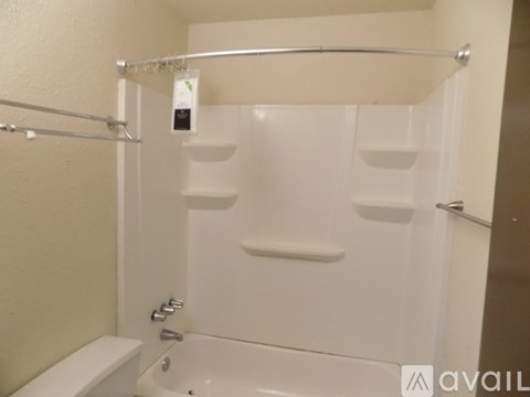 A white bathtub with a shower head and a towel bar.