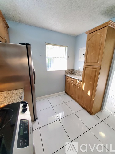A kitchen with a stainless steel refrigerator and a wooden cabinet.