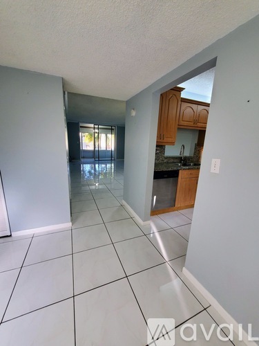 A spacious kitchen with wooden cabinets and a tiled floor.