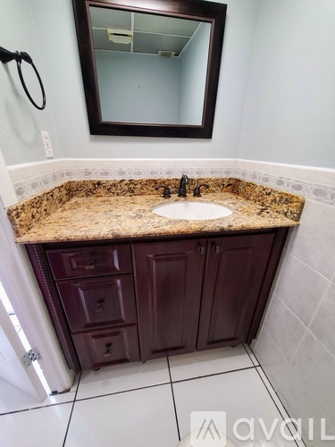 A bathroom with a granite countertop and a large mirror above the sink.