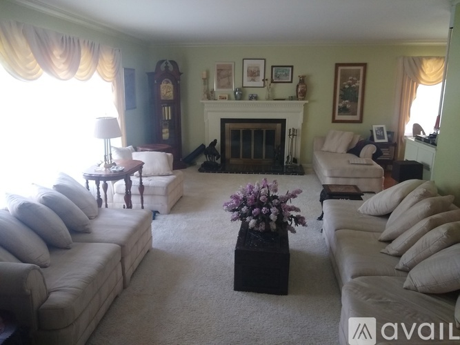 A living room with a white couch, a coffee table with flowers, and a fireplace.