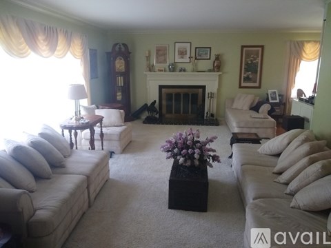 A living room with a white couch, a coffee table with flowers, and a fireplace.