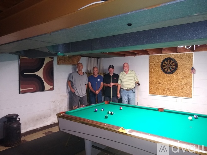 Four men are standing around a pool table.