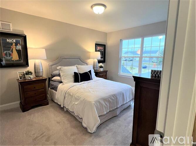 A bedroom with a large bed, a nightstand with a lamp, and a framed picture on the wall.