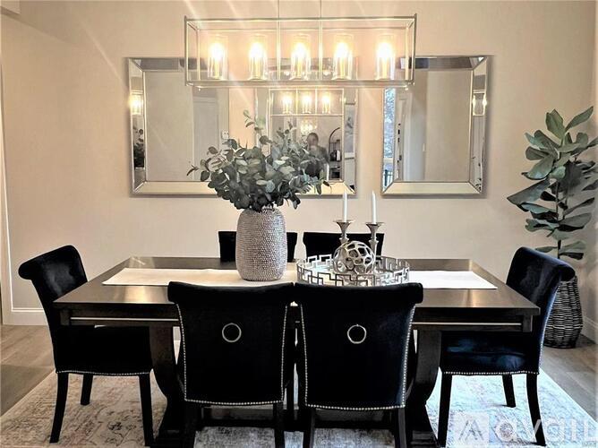 A dining room with a table set for two and a chandelier.