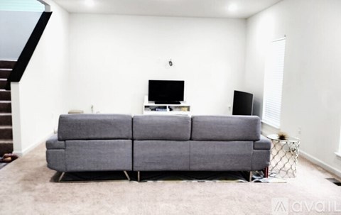A grey couch sits in a living room with a television and a black speaker on top of it.