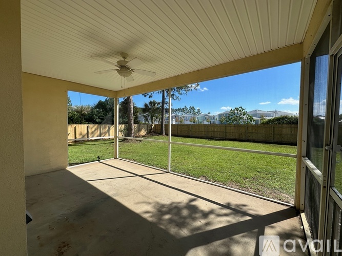A patio with a ceiling fan and sliding glass doors overlooking a grassy area.