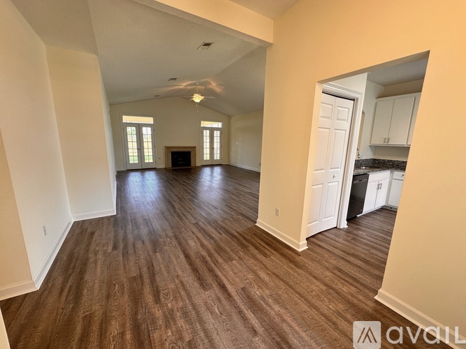 A spacious room with wood flooring and a ceiling fan.