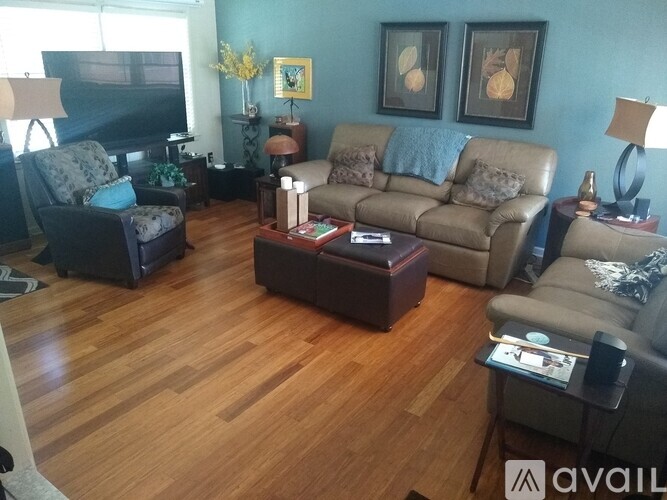A living room with a brown leather couch and a wooden floor.
