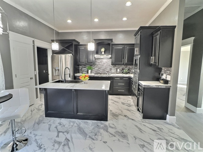A modern kitchen with black cabinets and a marble floor.