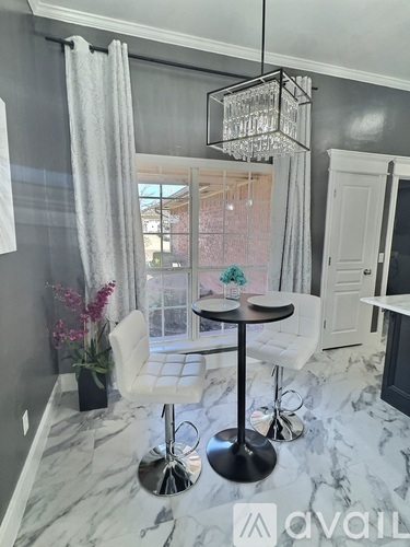 A dining area with a round table and white chairs.