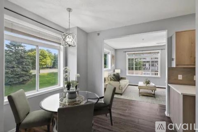 A modern dining room with a table set for two and a view of the backyard.