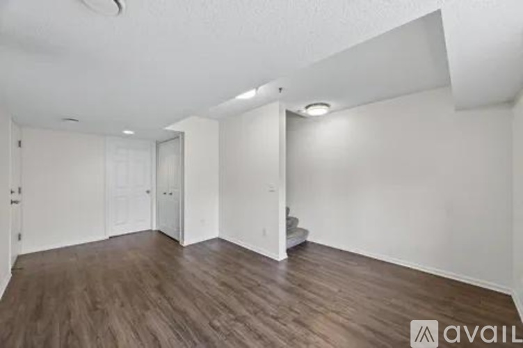 A spacious room with wooden flooring and white walls.