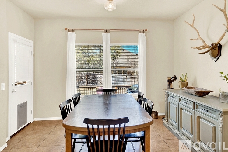 A dining room with a large table and chairs.