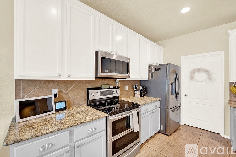 A kitchen with white cabinets and a granite counter top.