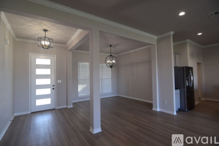 A spacious room with wooden floors and a large window with blinds.