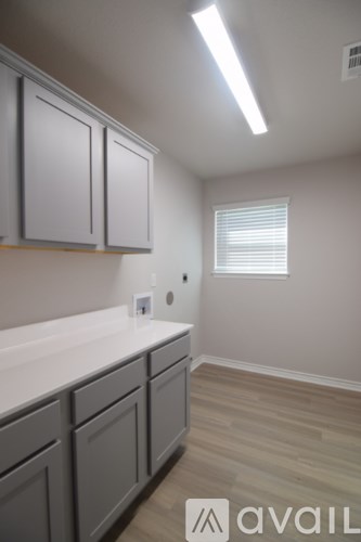 A kitchen with grey cabinets and a window with blinds.