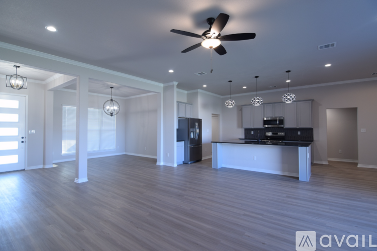 A spacious living room with a ceiling fan and hardwood flooring.