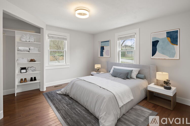 A bedroom with a large bed, a nightstand with a lamp, and a shelf with shoes and bags.