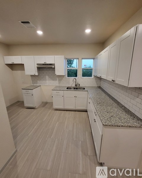 A kitchen with white cabinets and a granite countertop.