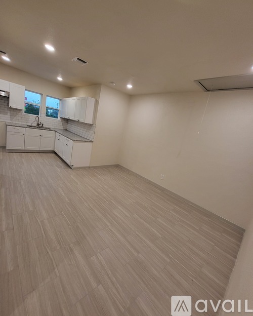 A spacious room with wooden flooring and white walls.