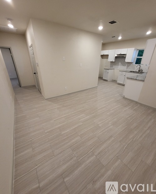 A spacious kitchen with white cabinets and a tiled floor.