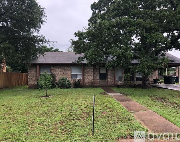 A house with a brown roof and a small tree in the front yard.