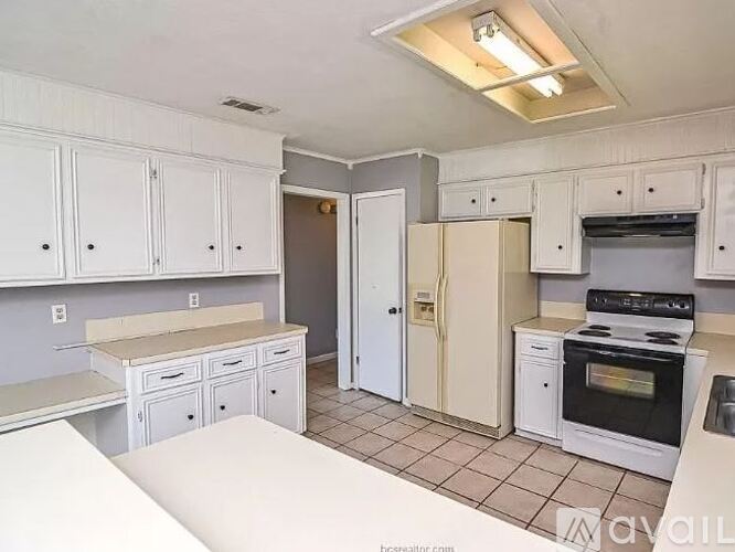 A kitchen with white cabinets and a black stove top oven.