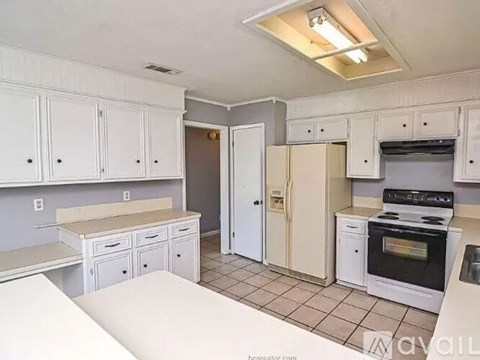 A kitchen with white cabinets and a black stove top oven.