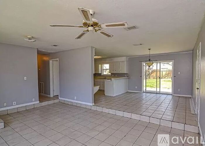 A spacious living room with a ceiling fan and tiled flooring.