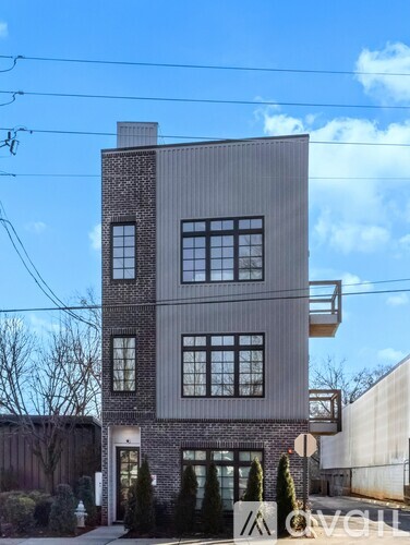 A modern two-story building with a flat roof and a balcony on the upper floor.