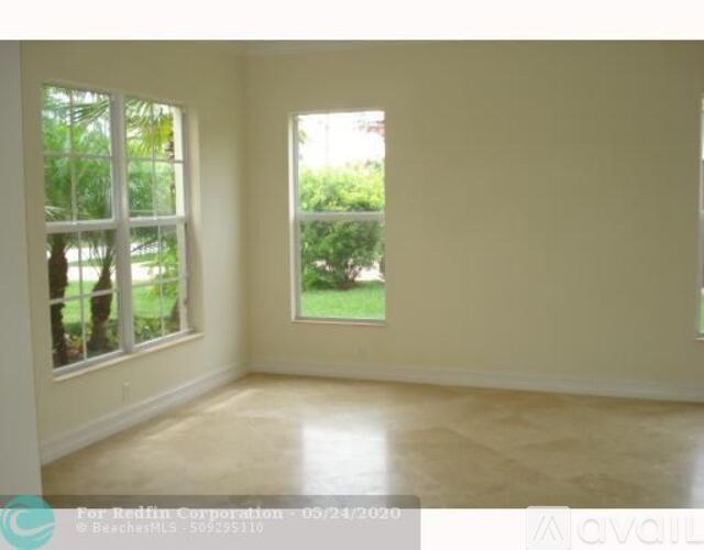 A room with two windows and a view of a garden outside.