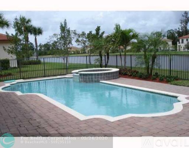 A pool surrounded by a black fence and brick pavers.