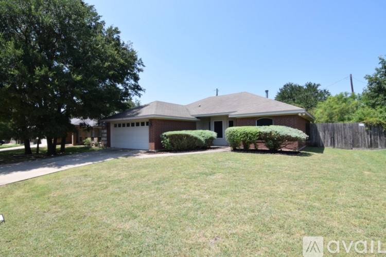 A house with a brown roof and a white garage door is surrounded by a green lawn.