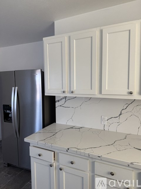 A kitchen with a marble countertop and white cabinets.