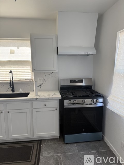 A kitchen with a black stove top oven and white cabinets.