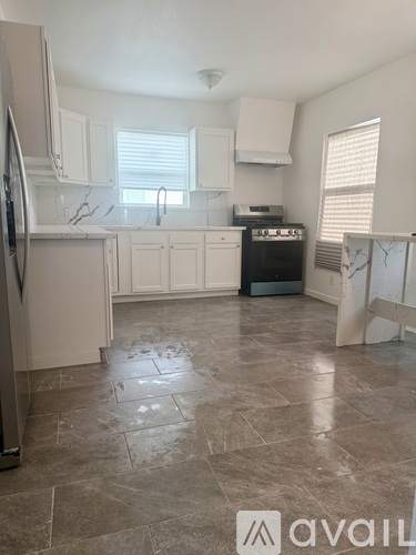 A kitchen with a tile floor and a refrigerator.