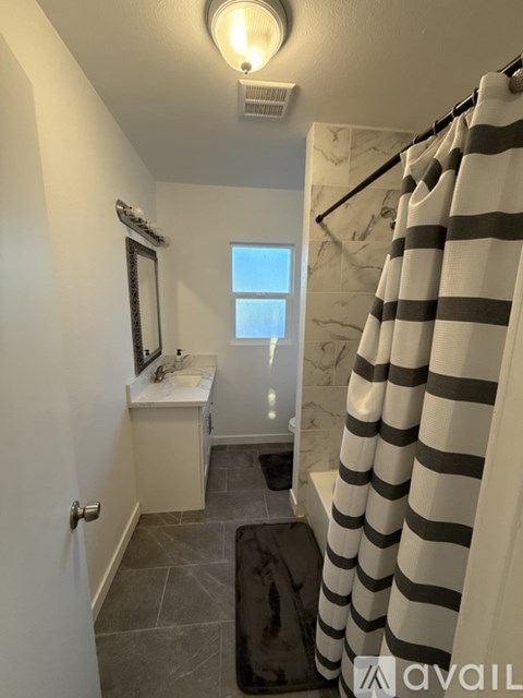 A bathroom with a striped shower curtain and a window.
