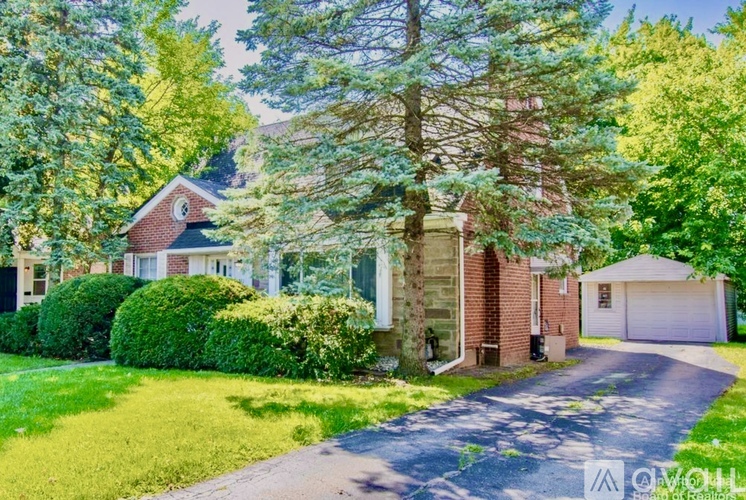 A house with a driveway and trees in front.