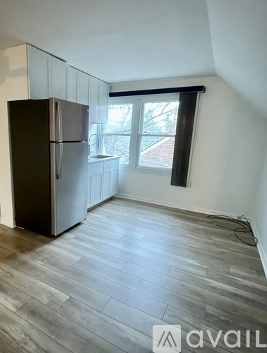 A kitchen with a black fridge and wooden flooring.