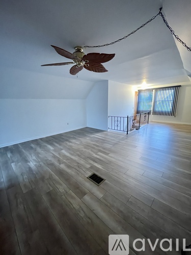 A room with a ceiling fan and wooden flooring.