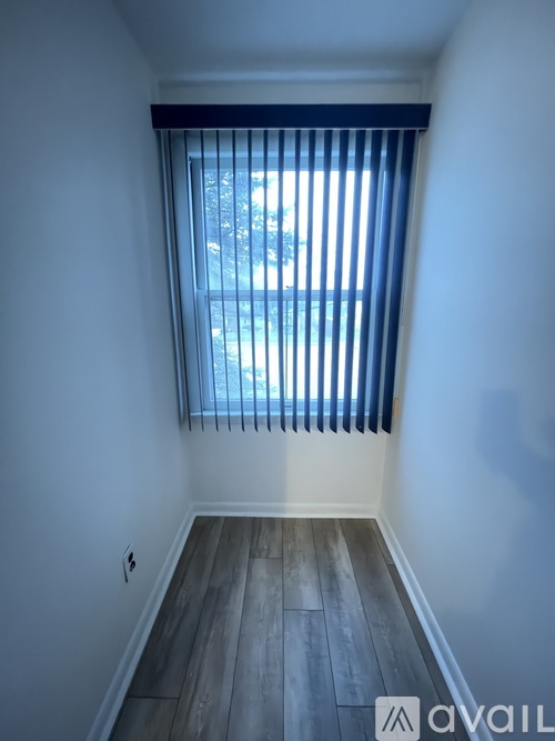 A room with a window covered by blue blinds.