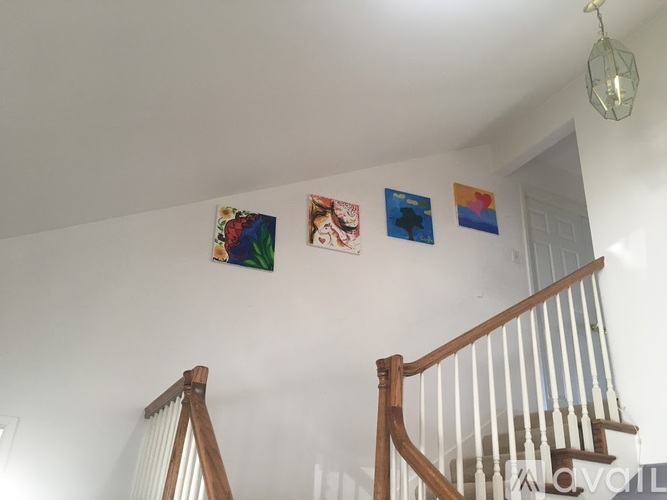 A living room with a staircase and four pictures on the wall.