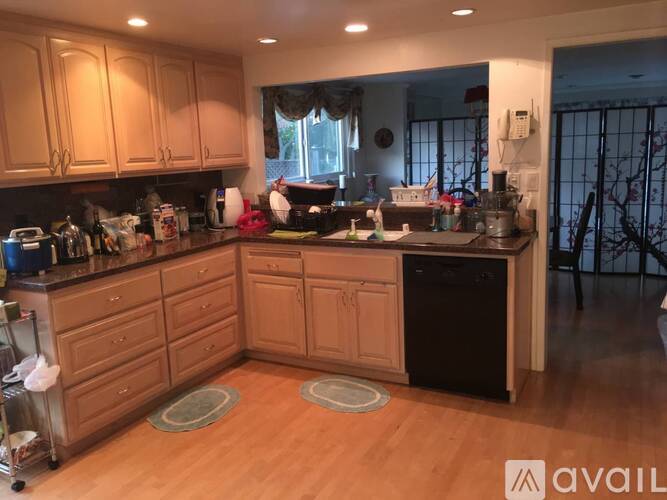 A kitchen with wooden cabinets and a black dishwasher.