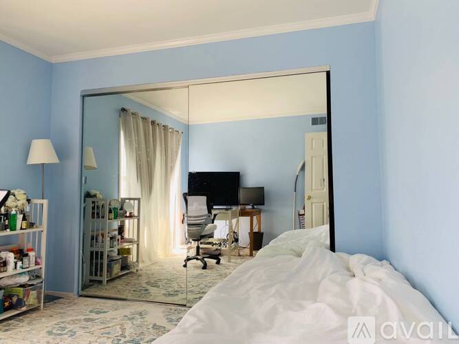 A bedroom with a large bed and a mirrored closet door.