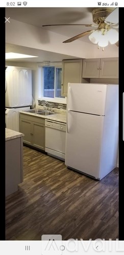 A kitchen with a white refrigerator and wooden flooring.