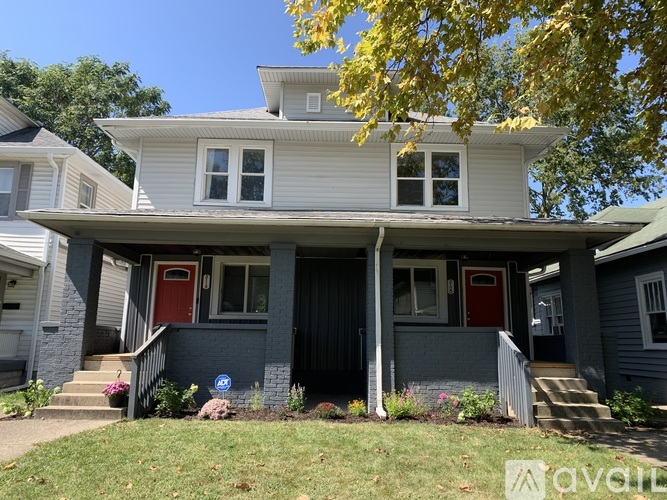 A two-story house with a red door and a balcony.
