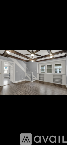 A spacious room with wooden floors and a staircase.