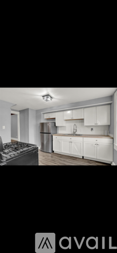 A modern kitchen with white cabinets and a black fridge.
