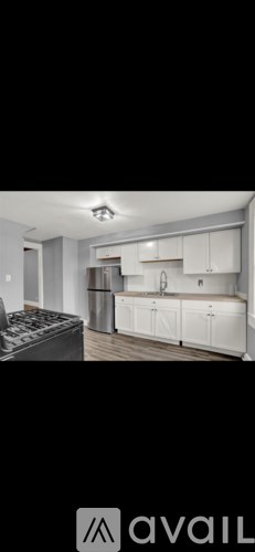 A modern kitchen with white cabinets and a black fridge.